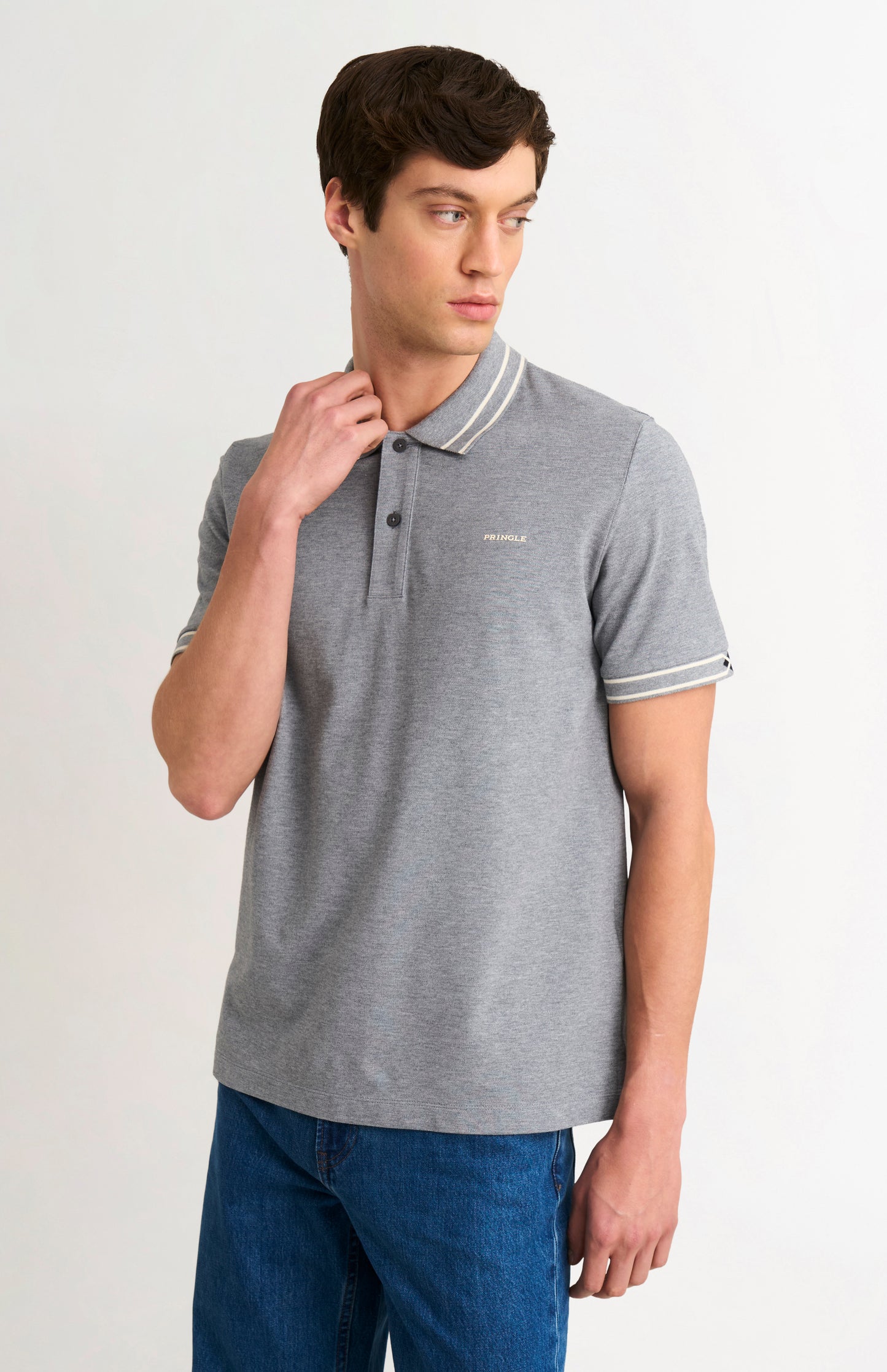 Man wearing a gray polo shirt with white trim on a plain background