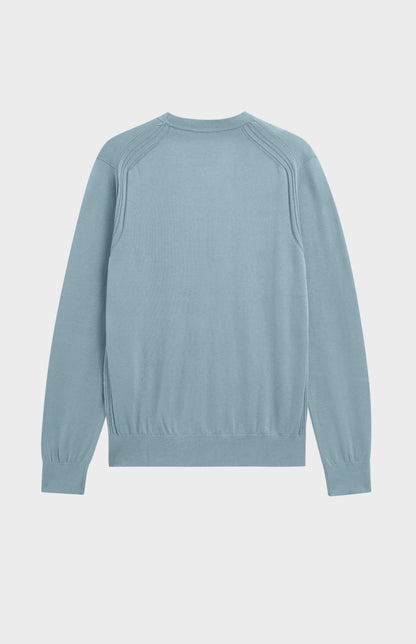A light blue long-sleeve knit sweater shown from the back, featuring raglan-style shoulder seams, on a light gray background.