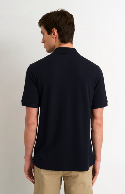 Man wearing a navy polo shirt on a plain background