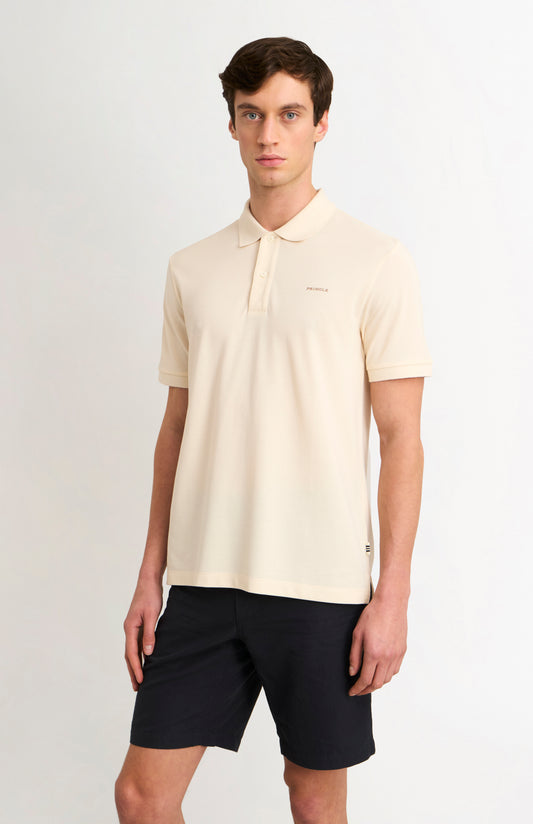 Man wearing a beige polo shirt and black shorts on a white background