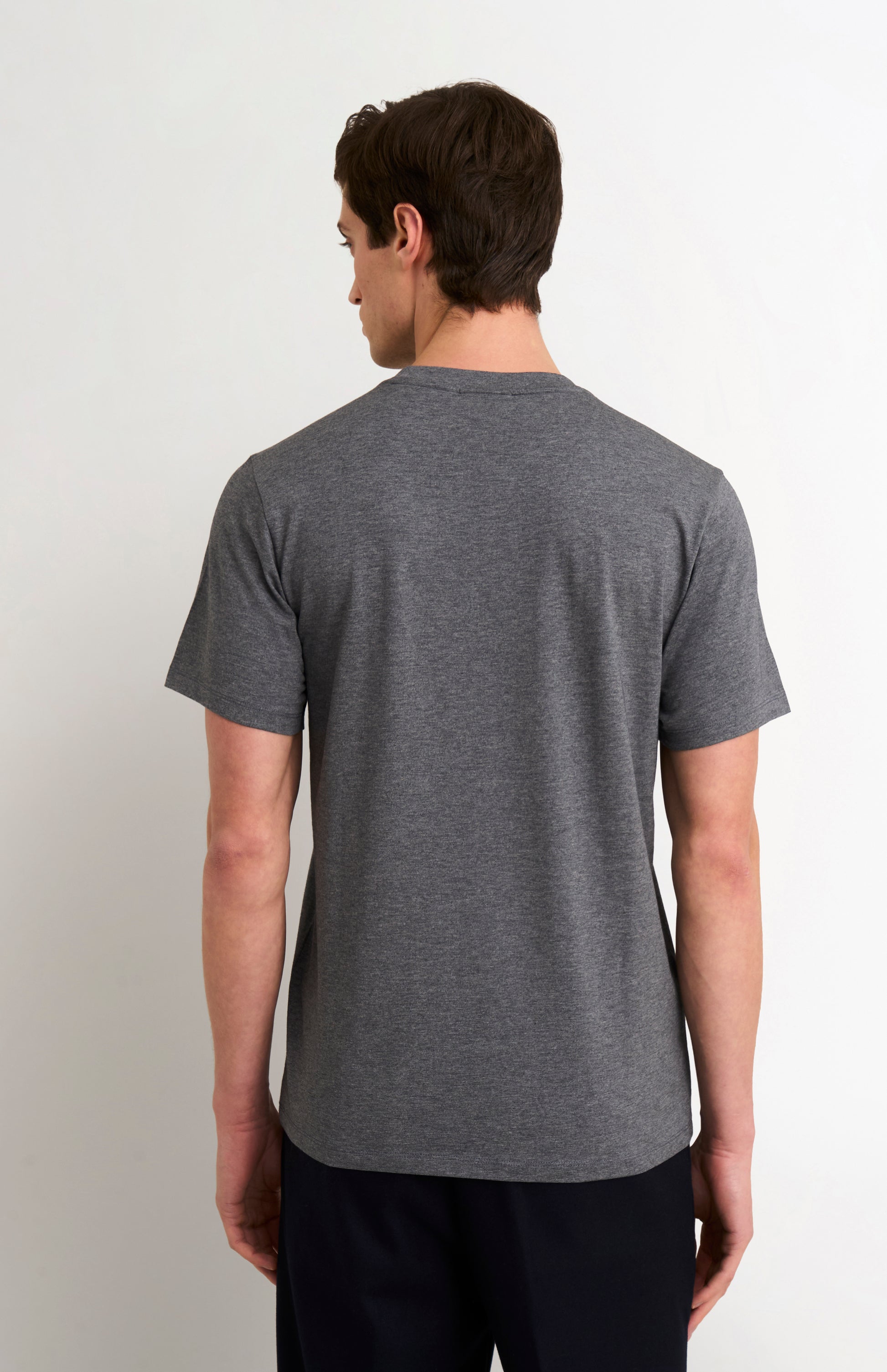 man wearing a charcoal t-shirt and black trousers on a white background