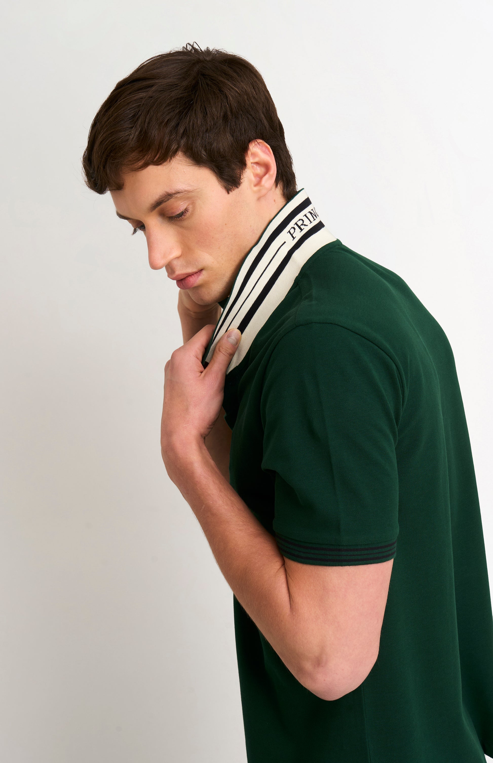 Detail shot of model wearing a forest green polo with tipping details and PRINGLE under flipped-up collar